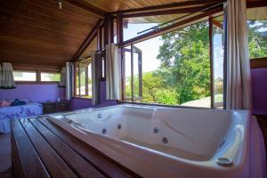 a large bath tub in a room with a window at Caiowa Floripa guesthouse in Florianópolis