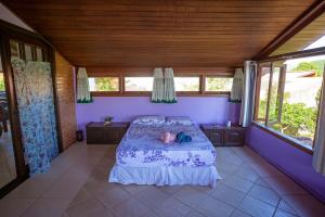 a bedroom with a bed with purple walls and windows at Caiowa Floripa guesthouse in Florianópolis