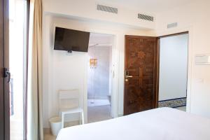 - une chambre avec un lit, une télévision et une salle de bains dans l'établissement Posada Boutique El Gallo Morón, à Morón de la Frontera