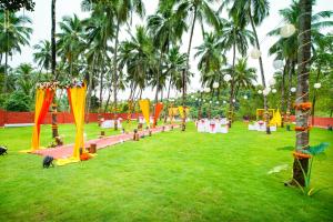 a park with palm trees and a group of tables at Amoravida By 7 Apple Resorts, Goa in Mandrem +52 photos