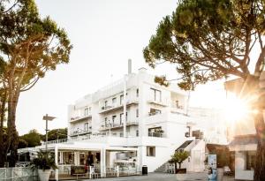 un bâtiment blanc avec des arbres devant lui dans l'établissement Stay Michelangelo Jesolo Only Adults, à Lido di Jesolo