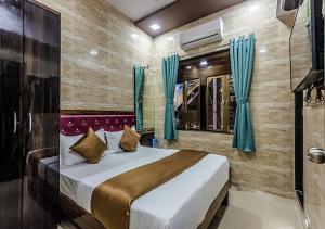 a bedroom with a bed and a television in it at Hotel Plaza- Near Byculla Railway Station in Mumbai