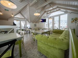 a restaurant with a green couch and tables and windows at Villa Shale MarSo in Bukovel