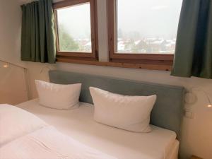 a bedroom with a bed with two pillows and two windows at Feine FeWo im DG für 3 am Tegernsee in Bad Wiessee