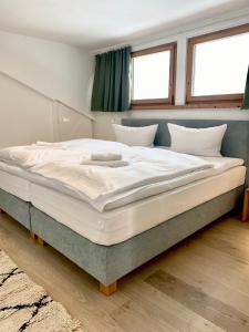 duże łóżko w pokoju z 2 oknami w obiekcie Feine FeWo im DG für 3 am Tegernsee w mieście Bad Wiessee