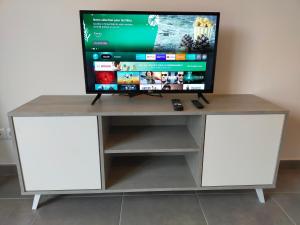 a tv on top of a white tv stand at Maison individuelle neuve plein pied avec terrasse et jardin clos 15 minutes a pied de la plage arrivé a partir de 15h30 in Quiberville