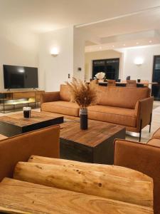 een woonkamer met banken en tafels en een tv bij Le Pact - Gîte familial in Anhée