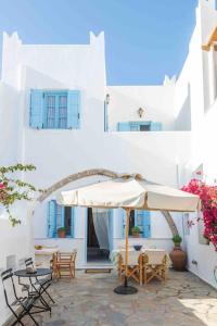 eine Terrasse mit einem Sonnenschirm, Stühlen und Tischen in der Unterkunft Traditional Two Story House in Galanado Naxos in Galanádhon