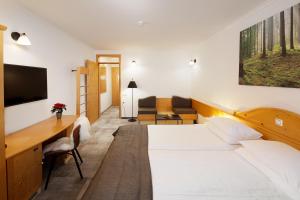 una camera d'albergo con 2 letti e una scrivania di Hotel Planja a Zreče