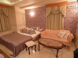 ein Schlafzimmer mit einem Bett, einer Couch und einem Tisch in der Unterkunft Hotel VINO Adult Only in Kawaguchi