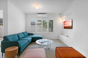 a living room with a blue couch and a table at Mediterranean Surfers Paradise Townhouse with BBQ in Gold Coast