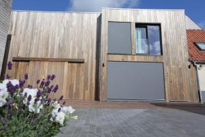 a wooden building with a large door with a large window at De Panne - Adinkerke - 't Voetbrugsje comfortabele nieuwbouw in De Panne