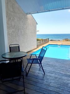 un patio con mesa y sillas junto a una piscina en La Falaise Sea Front Villa, en Flic en Flac