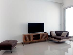 sala de estar con TV de pantalla plana y 2 sillas en La Falaise Sea Front Villa, en Flic en Flac