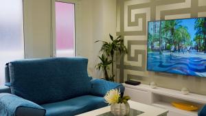 salon z niebieskim krzesłem i telewizorem z płaskim ekranem w obiekcie Spacious Modern Family Apartment - Centre & Near Beach w Alicante