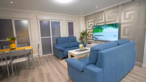 een woonkamer met twee blauwe stoelen en een televisie bij Spacious Modern Family Apartment - Centre & Near Beach in Alicante