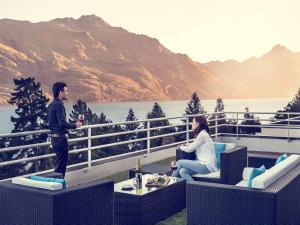 
two people sitting on a bench in front of a lake at Mercure Queenstown Resort in Queenstown
