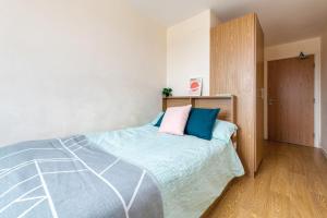 um quarto com uma cama com almofadas azuis e cor-de-rosa em For Students Only Private Bedroom with Shared Kitchen at Athena Hall in Ipswitch em Ipswich