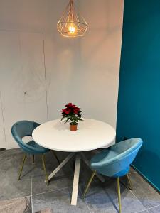 einen weißen Tisch mit zwei blauen Stühlen und eine Vase mit einer Pflanze in der Unterkunft ORLANDO relais in Neapel
