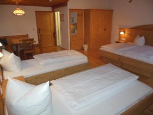 Zimmer mit 3 Betten und einem Tisch mit Tisch in der Unterkunft Gasthof Pension Altwirt in Sachsenkam