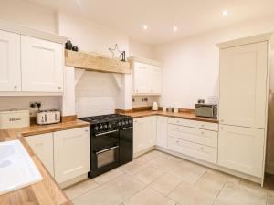een keuken met witte kasten en een zwarte oven bij Cavendish Cottage in Matlock