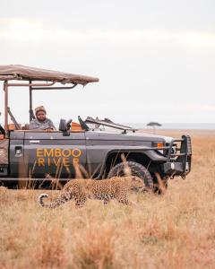 a man in a jeep with a leopard in a field at Emboo River Camp in Talek