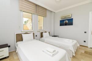 Dos camas en una habitación con paredes y ventanas blancas. en Villa Moonlight, en Karadere 56 fotos más