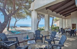 un patio con sedie, tavoli e l'oceano di Villa Les 3 frères a San-Nicolao
