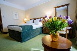 um quarto de hotel com uma cama e um vaso de flores sobre uma mesa em Hotel HP Tower One Brasov em Braşov
