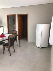 uma cozinha com uma mesa e um frigorífico branco em Quiosque 1 em Joanópolis