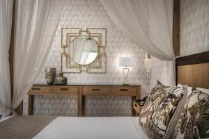 a bedroom with a bed with a mirror and a dresser at Hotel Matheo Villas & Suites in Malia