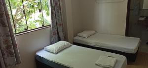 two beds in a room with a window at D'Casa Hotel e restaurante in Marechal Cândido Rondon