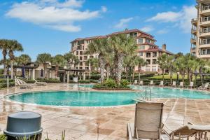 a swimming pool with chairs in front of a building at Sea Dunes Penthouse in Fernandina Beach
