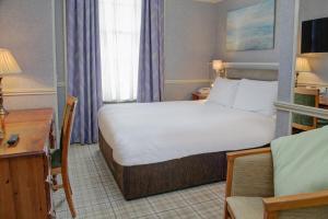 a hotel room with a bed and a desk and a chair at Old Hunstanton Le Strange Arms Hotel in Hunstanton