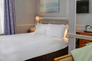 a bedroom with a large bed with white sheets and pillows at Old Hunstanton Le Strange Arms Hotel in Hunstanton