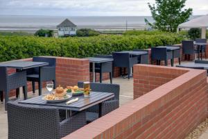 a patio with tables and chairs with a plate of food at Old Hunstanton Le Strange Arms Hotel in Hunstanton