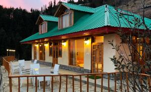 a house with a green roof and white chairs at Jomotel Talai in Cheog