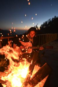 a man playing a guitar over a fire at Jomotel Talai in Cheog