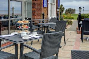 a table and chairs on a patio with food on it at Old Hunstanton Le Strange Arms Hotel in Hunstanton