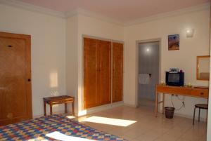 Hotel Aladarissa Ait Baha في Aït Taksimt: غرفة نوم بسرير ومكتب وتلفزيون