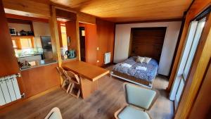 a bedroom with a bed and a desk and a kitchen at Hermoso monoambiente con jardin, modernoso y cálido a media cuadra de la calle principal (V406) in San Martín de los Andes