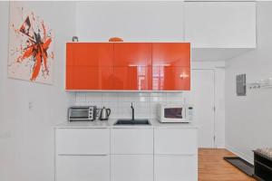 cocina con armarios blancos y naranjas y microondas en INITIAL - ORANGE studio - Centre-Ville de Québec, en Quebec