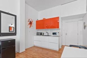 una cocina con armarios blancos y un armario naranja en INITIAL - ORANGE studio - Centre-Ville de Québec, en Quebec