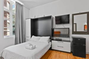 1 dormitorio con 1 cama blanca y TV en INITIAL - ORANGE studio - Centre-Ville de Québec, en Quebec