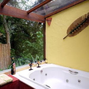 a bath tub in a room with a window at Pousada Paraíso Açú in Itaipava