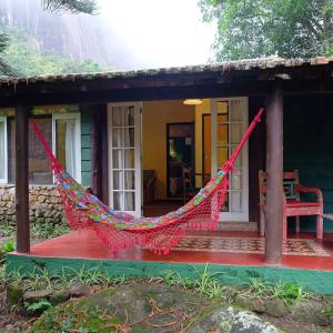 uma casa com uma rede em frente em Pousada Paraíso Açú em Itaipava