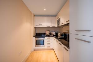 a small kitchen with white cabinets and a wooden floor at Impeccable 1-Bed Apartment in London City in London