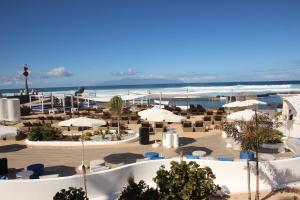 a resort with tables and umbrellas on the beach at Europe Villa Cortes GL in Playa de las Americas