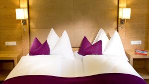 a bedroom with a white bed with purple pillows at Hotel Gambswirt in Tamsweg