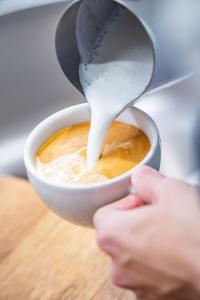 a person is pouring milk into a cup of coffee at la belle vue Boutique Hotel & Café in Spiez